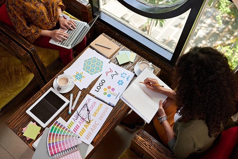Female designers working on logo for the website, view from the top